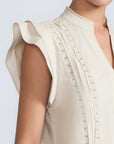 Pria Blouse in Prestine – Elegant sleeveless blouse in pima cotton with tonal V-neck, Greca trim, ruffle detail, and hem with pullers.