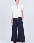 Pria Blouse in White – Sleeveless pima cotton blouse with V-neckline, Greca trim, tonal stitching, ruffle sleeves, and hem pullers.