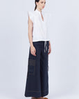 Pria Blouse in White – Sleeveless pima cotton blouse with V-neckline, Greca trim, tonal stitching, ruffle sleeves, and hem pullers.