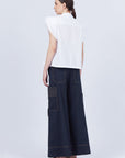 Pria Blouse in White – Sleeveless pima cotton blouse with V-neckline, Greca trim, tonal stitching, ruffle sleeves, and hem pullers.