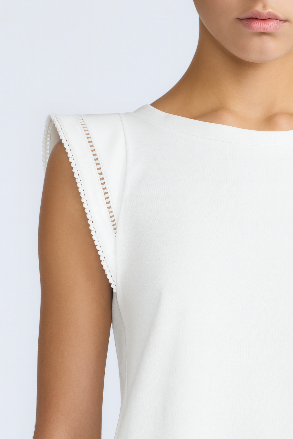 White sleeveless top with lace trim on a plain background