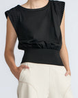 Black sleeveless top with textured shoulders worn by a person on a light gray background