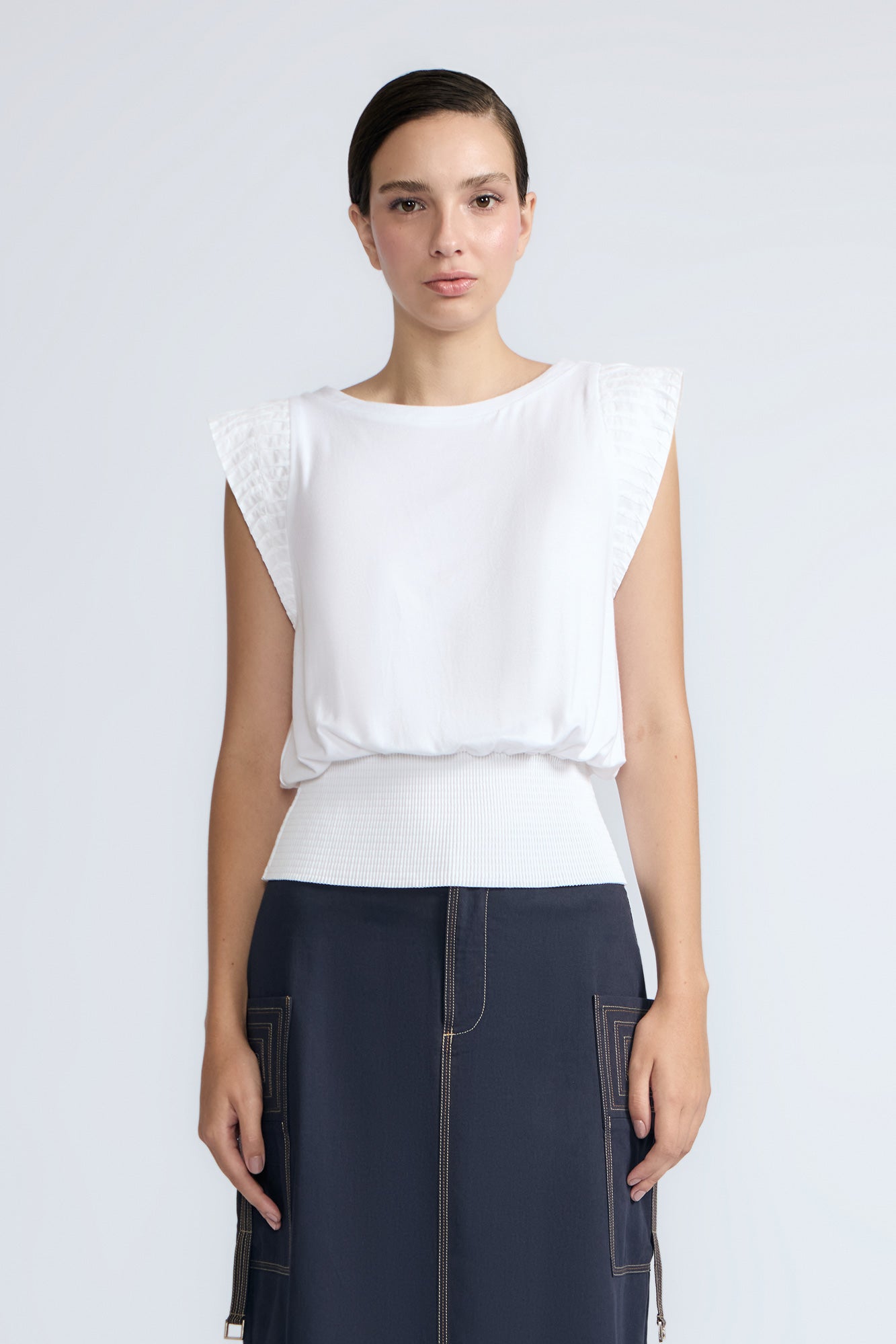 Selena Top in White – Soft cotton sleeveless top with round collar, ruffled arm details, and a gently cinched waist.