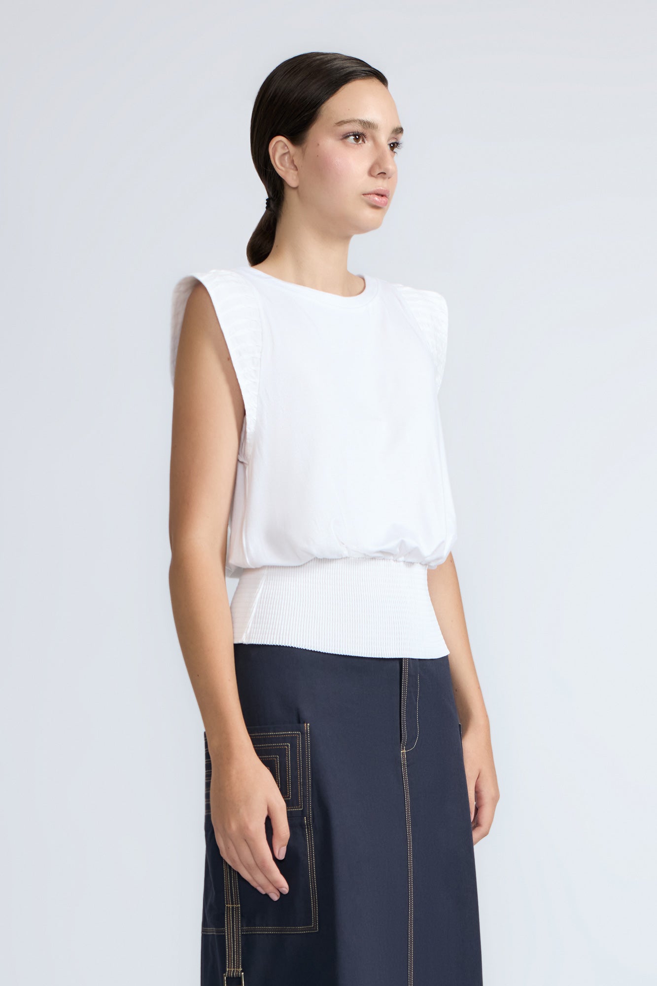 Selena Top in White – Soft cotton sleeveless top with round collar, ruffled arm details, and a gently cinched waist.