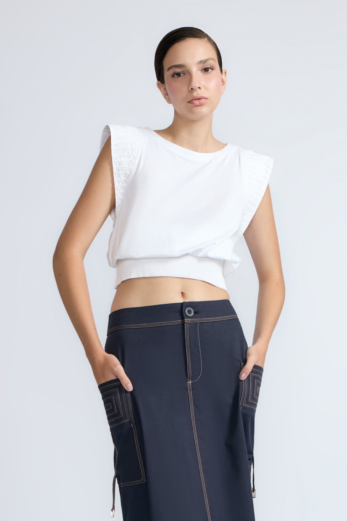 Selena Top in White – Soft cotton sleeveless top with round collar, ruffled arm details, and a gently cinched waist.
