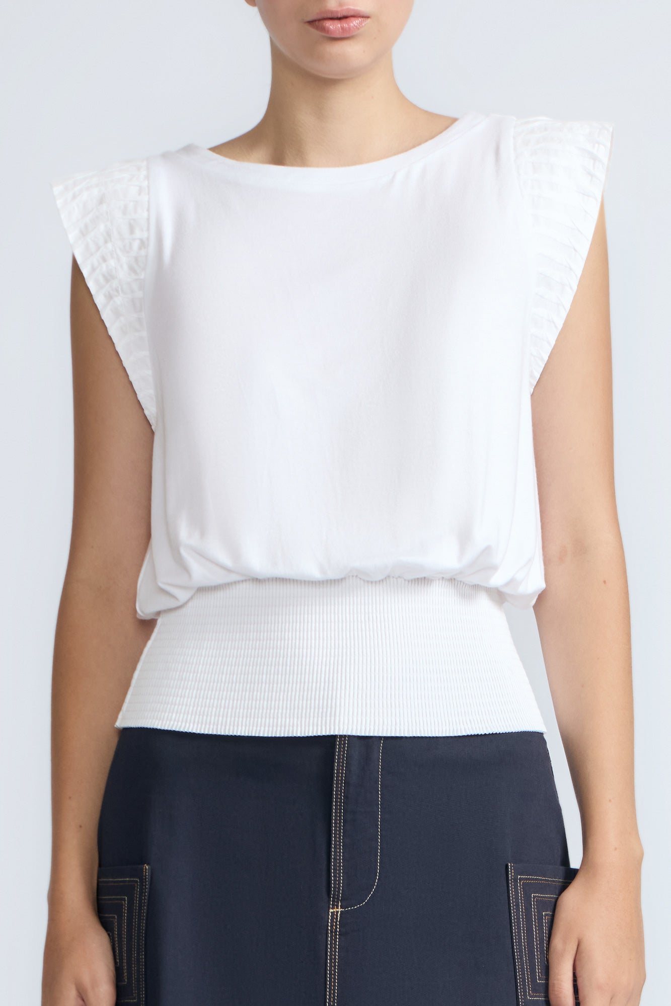 Selena Top in White – Soft cotton sleeveless top with round collar, ruffled arm details, and a gently cinched waist.