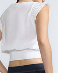 Selena Top in White – Soft cotton sleeveless top with round collar, ruffled arm details, and a gently cinched waist.