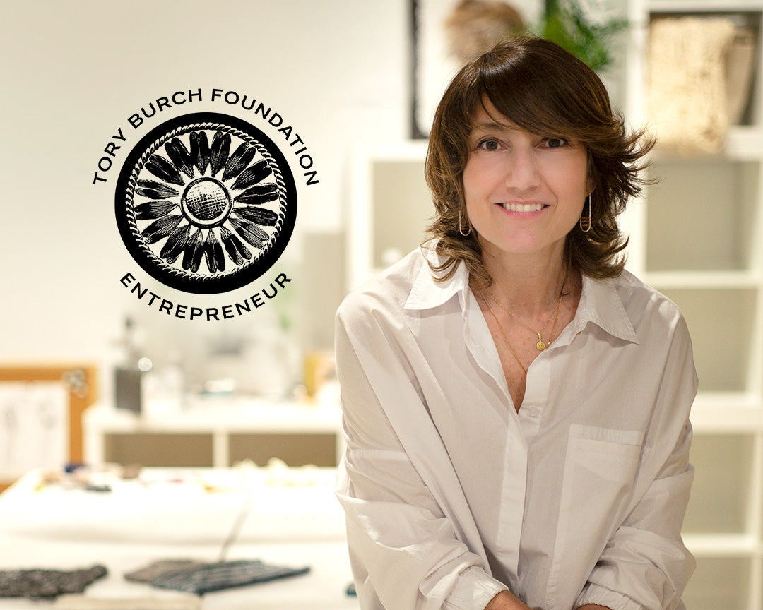 Woman in a white shirt sitting in a room with fabric, with the Tory Burch Foundation Entrepreneur logo.
