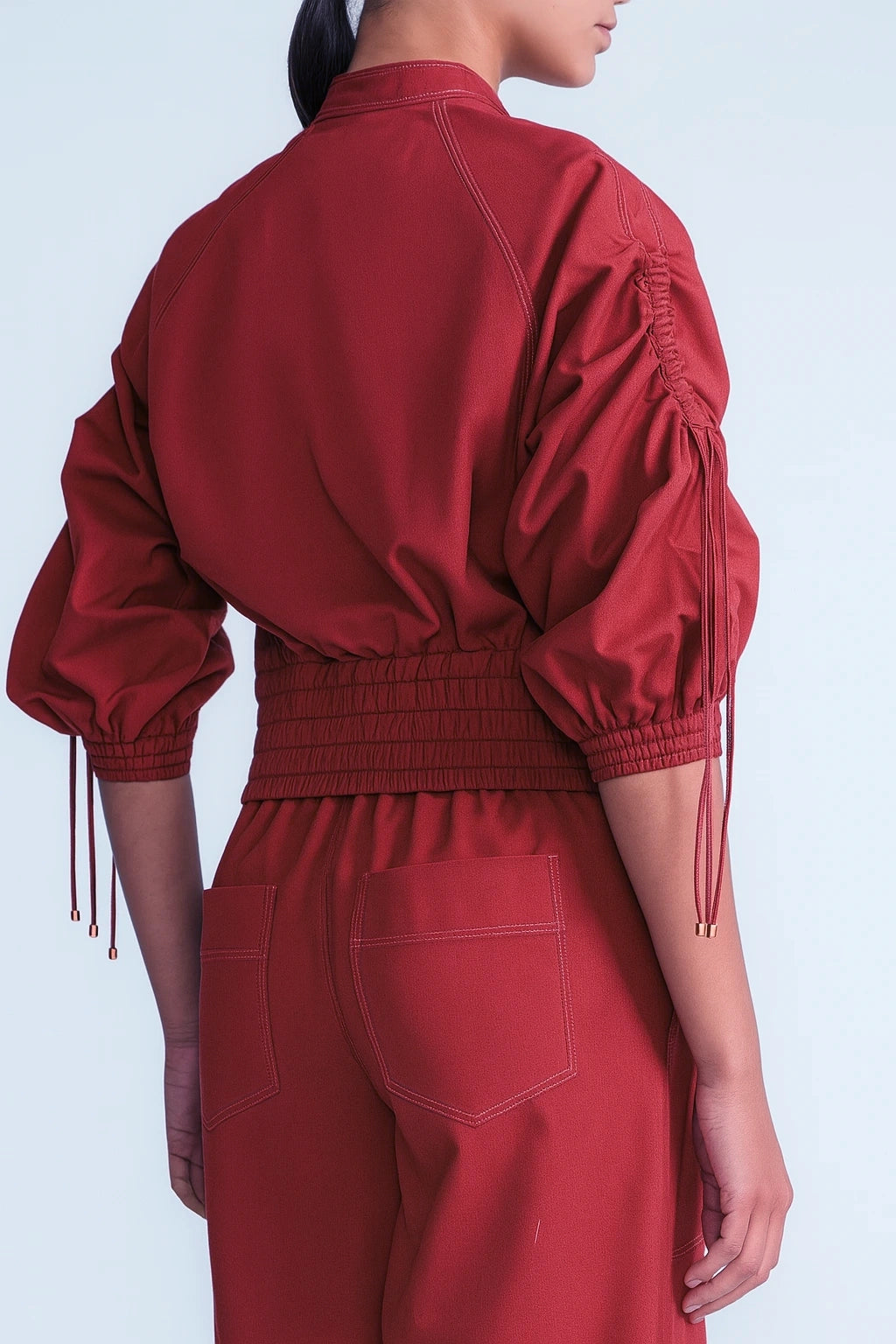 Red outfit with fringed sleeves on a light gray background