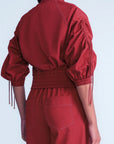 Red outfit with fringed sleeves on a light gray background