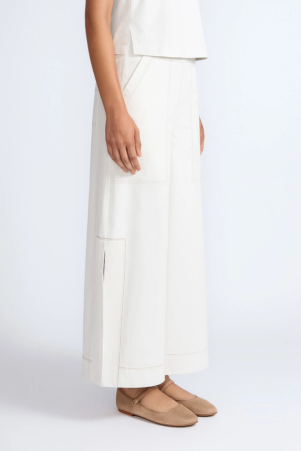 Person wearing a white outfit with beige shoes on a white background