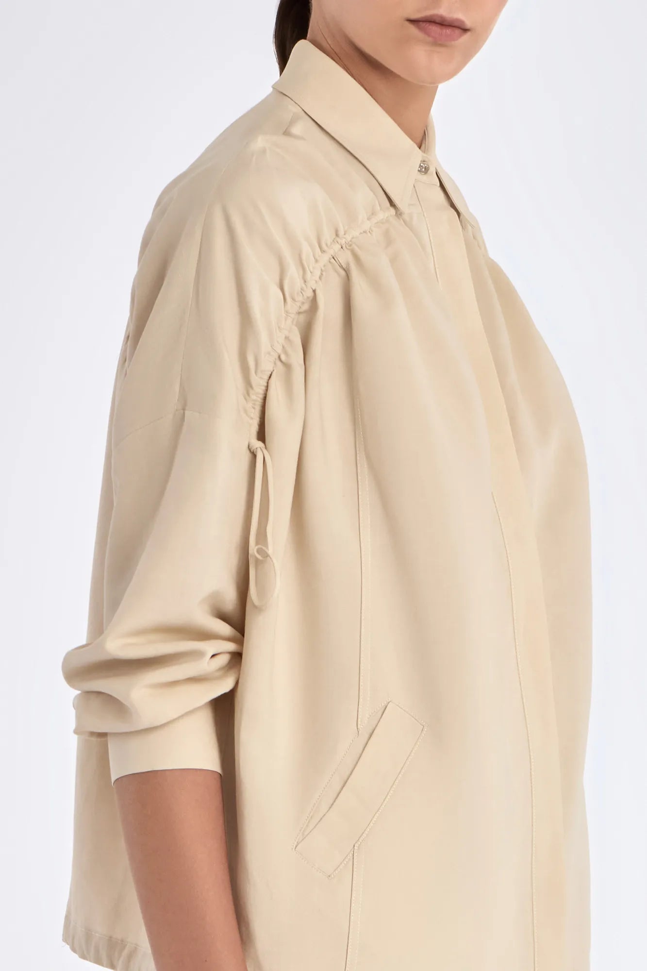 Side profile of the Ailani Jacket in a natural Ecru, featuring its unique drawstring placket.
