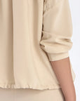 Close-up of the signature metal button and the natural texture of the linen blend on the Ecru Ailani Jacket.