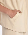 Close-up of the signature metal button and the natural texture of the linen blend on the Ecru Ailani Jacket.