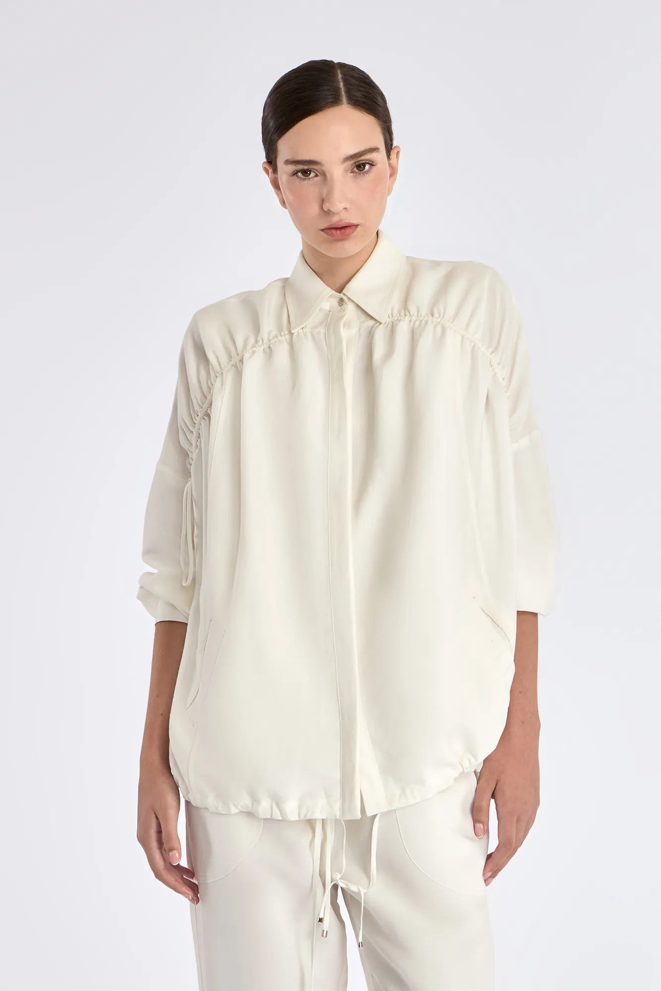 The Ailani Jacket in Off White, highlighting its clean architectural lines and drawstring detail.