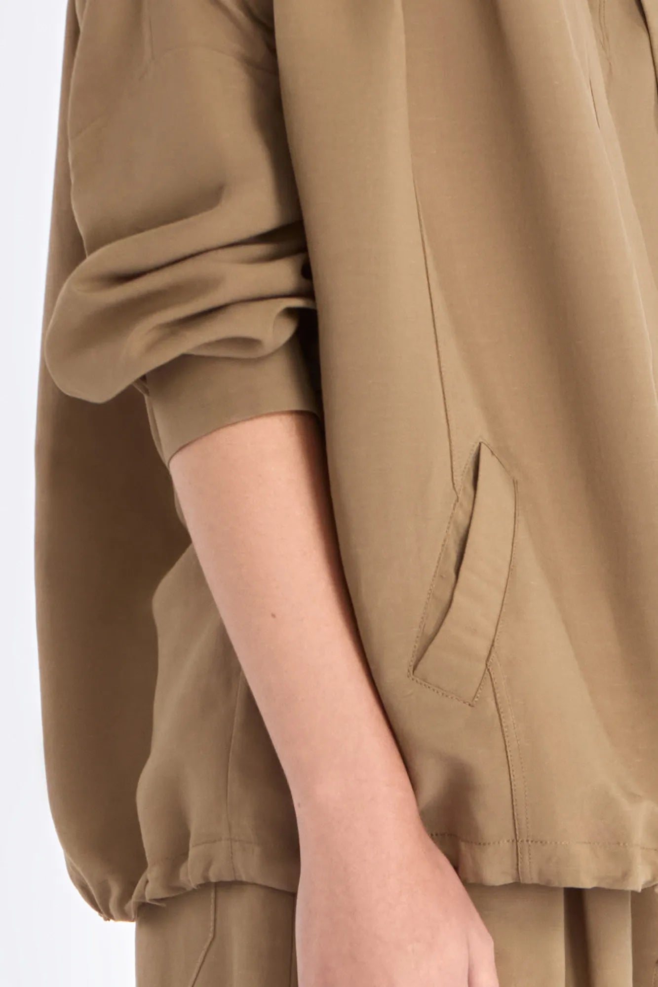 Close-up of the signature exposed metal button and adjustable drawstring on the Taupe Ailani Jacket.