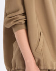 Close-up of the signature exposed metal button and adjustable drawstring on the Taupe Ailani Jacket.