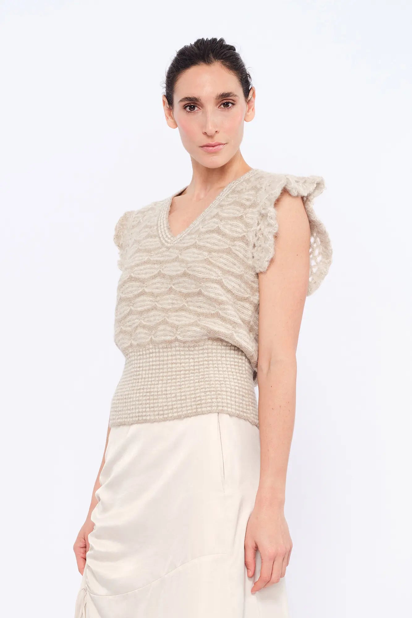 Front view of the Beca Vest in Beige Melange, showcasing the V-neckline and crochet ruffle sleeves.