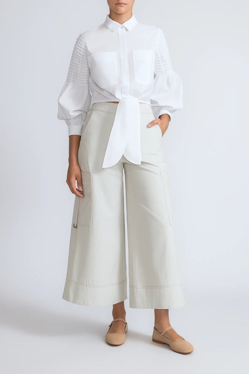 Person wearing a white shirt and light-colored pants on a plain background