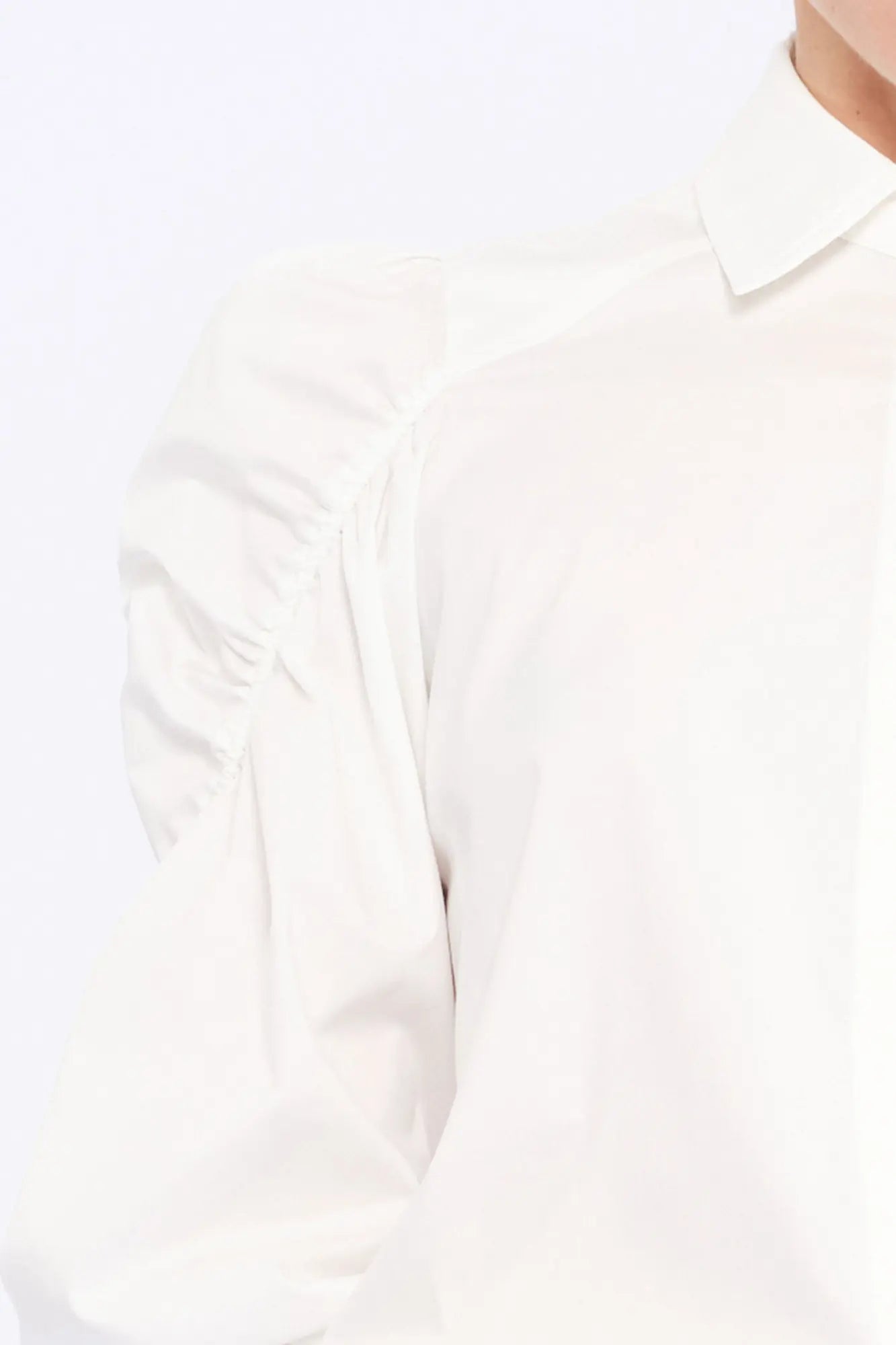 Detail shot of the sculptural puff sleeve and the premium cotton fabric of the white Bimba Blouse.