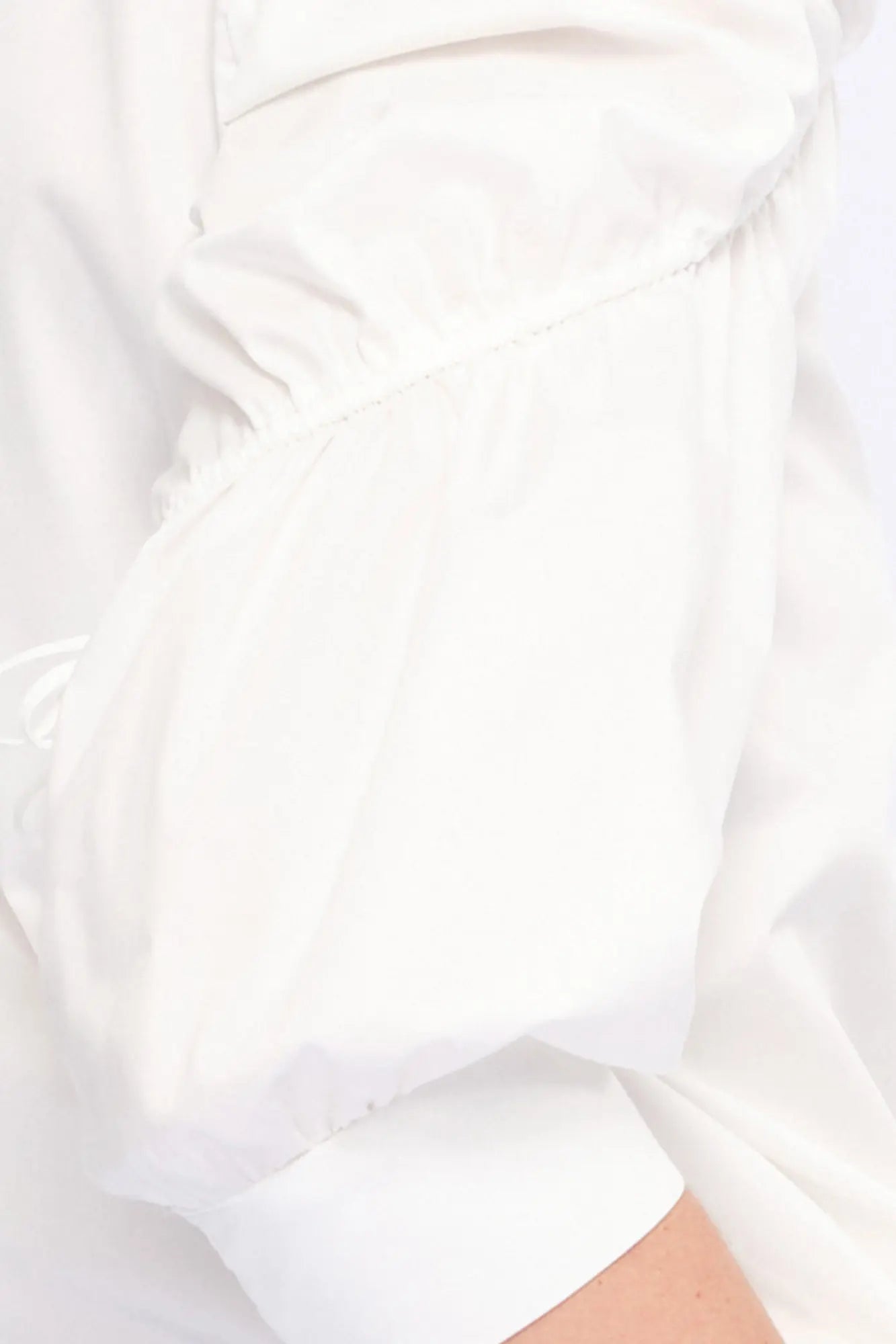 Detail shot of the sculptural puff sleeve and the premium cotton fabric of the white Bimba Blouse.