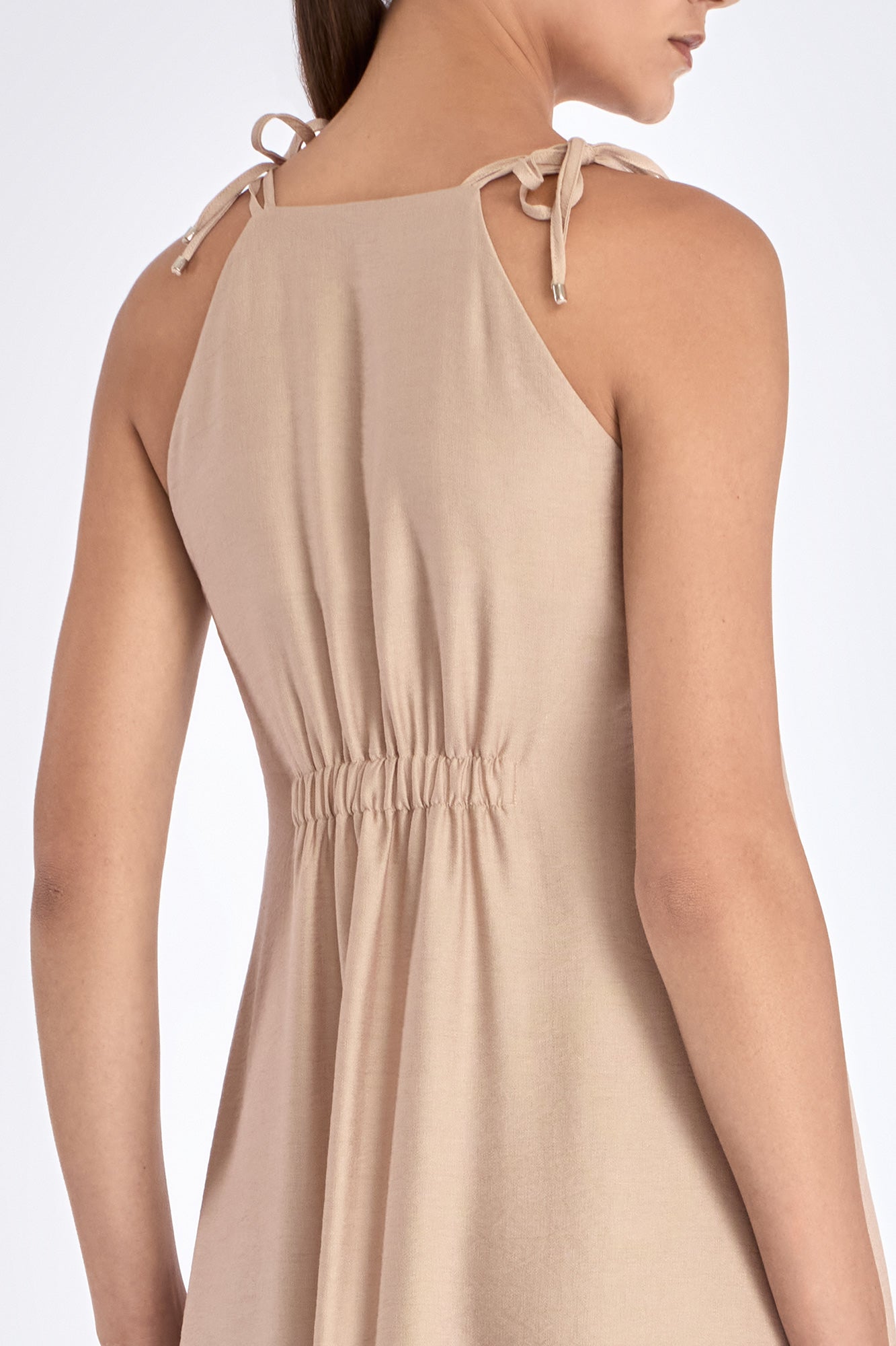 Blake Dress in Nude – Elegant long dress with delicate double straps, V-neck with ruffles, pleated skirt, and hidden side pockets.