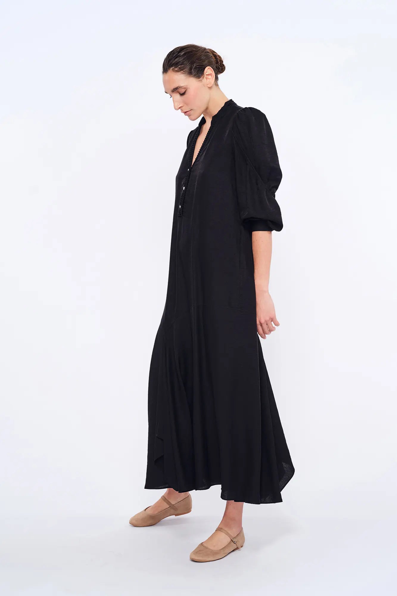 Side profile of the black Carlie Dress, highlighting the draped, asymmetrical skirt.