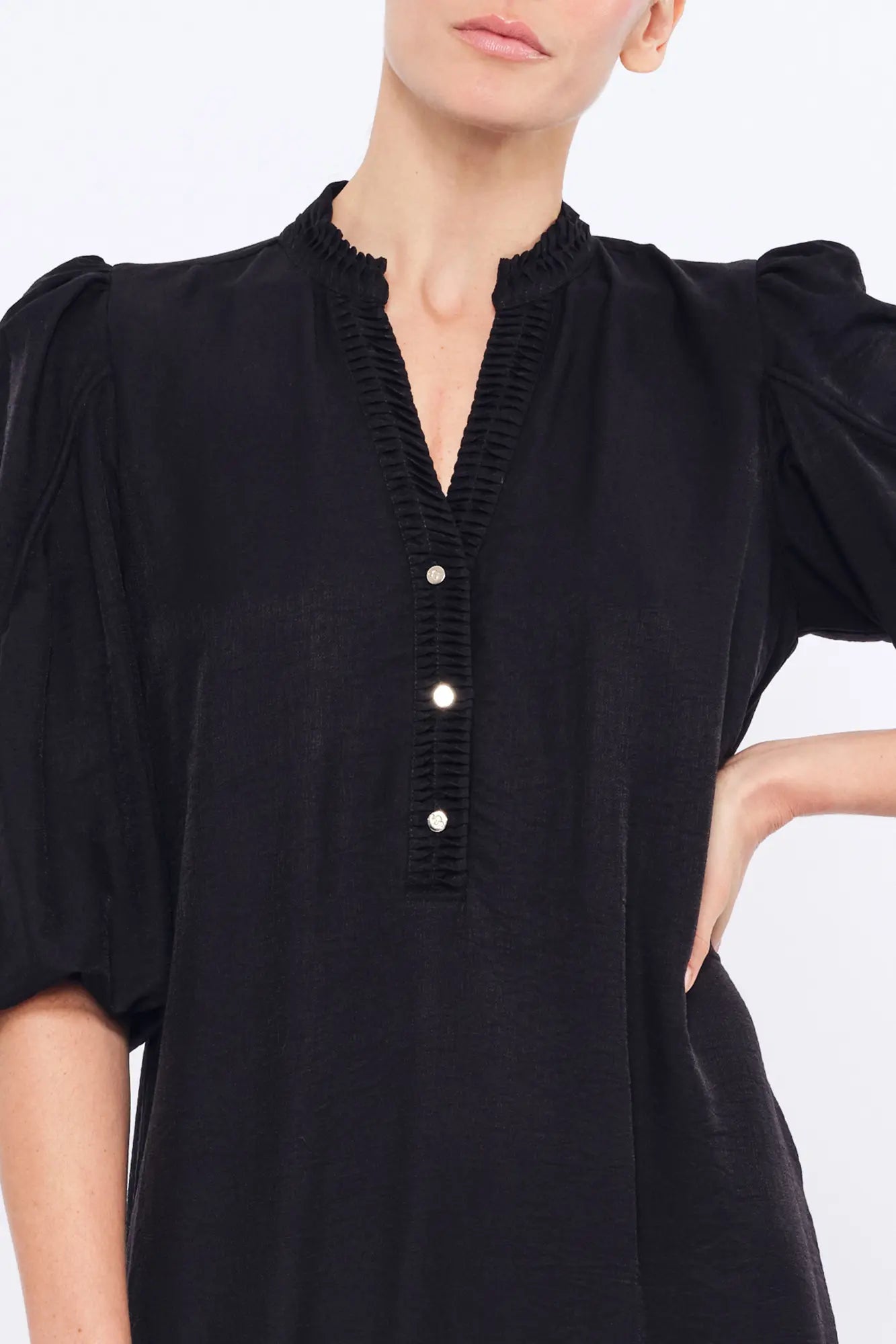 Close-up of the delicate gathers at the V-neckline of the black Carlie Dress.