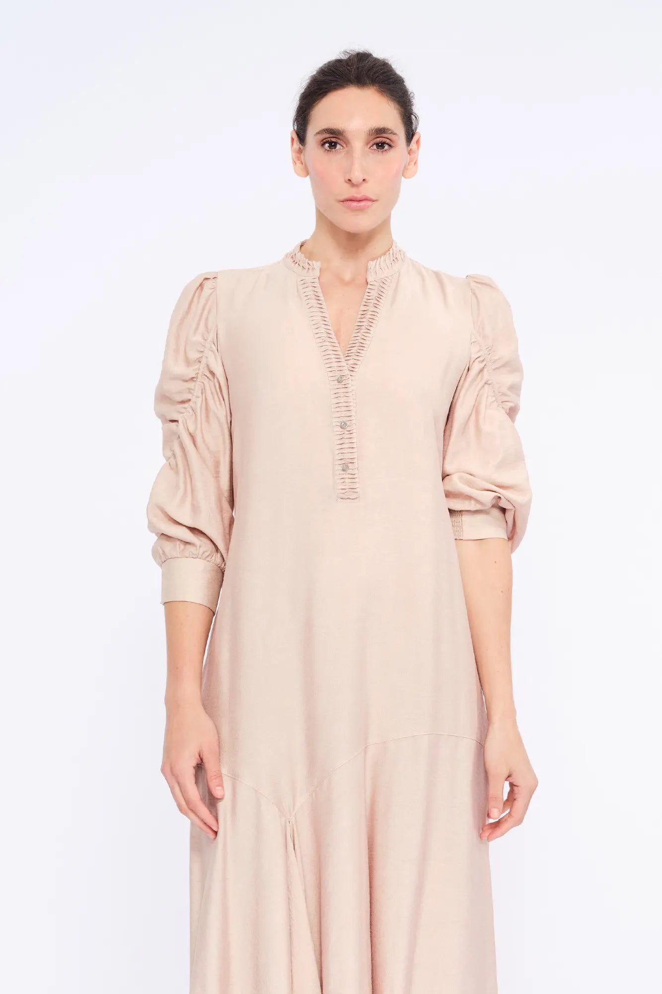 Front view of the Carlie Dress in Nude, showcasing its gathered V-neckline and asymmetrical skirt.

