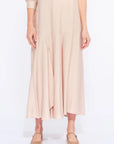 Front view of the Carlie Dress in Nude, showcasing its gathered V-neckline and asymmetrical skirt.