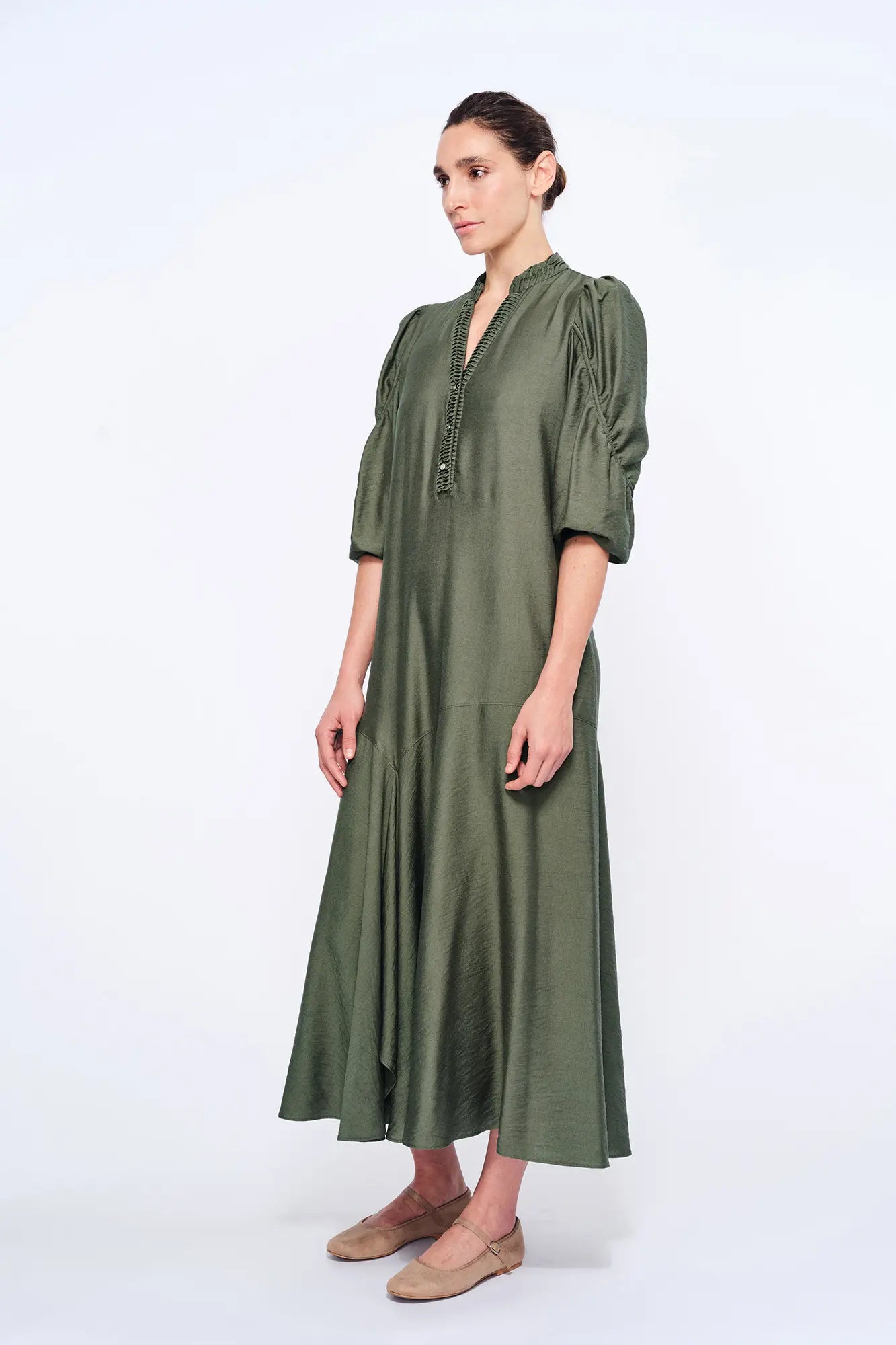 Side view of the Olive Carlie Dress, showcasing the elegant movement of its asymmetrical hem.