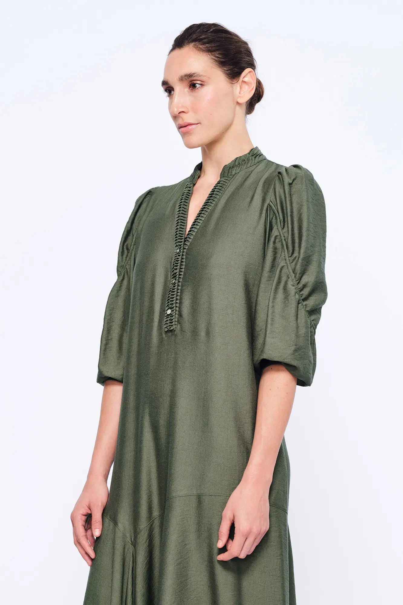 Side view of the Olive Carlie Dress, showcasing the elegant movement of its asymmetrical hem.