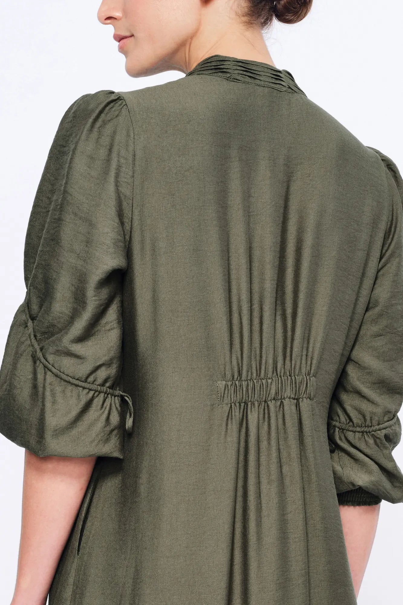 Side view of the Olive Carlie Dress, showcasing the elegant movement of its asymmetrical hem.