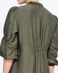 Side view of the Olive Carlie Dress, showcasing the elegant movement of its asymmetrical hem.