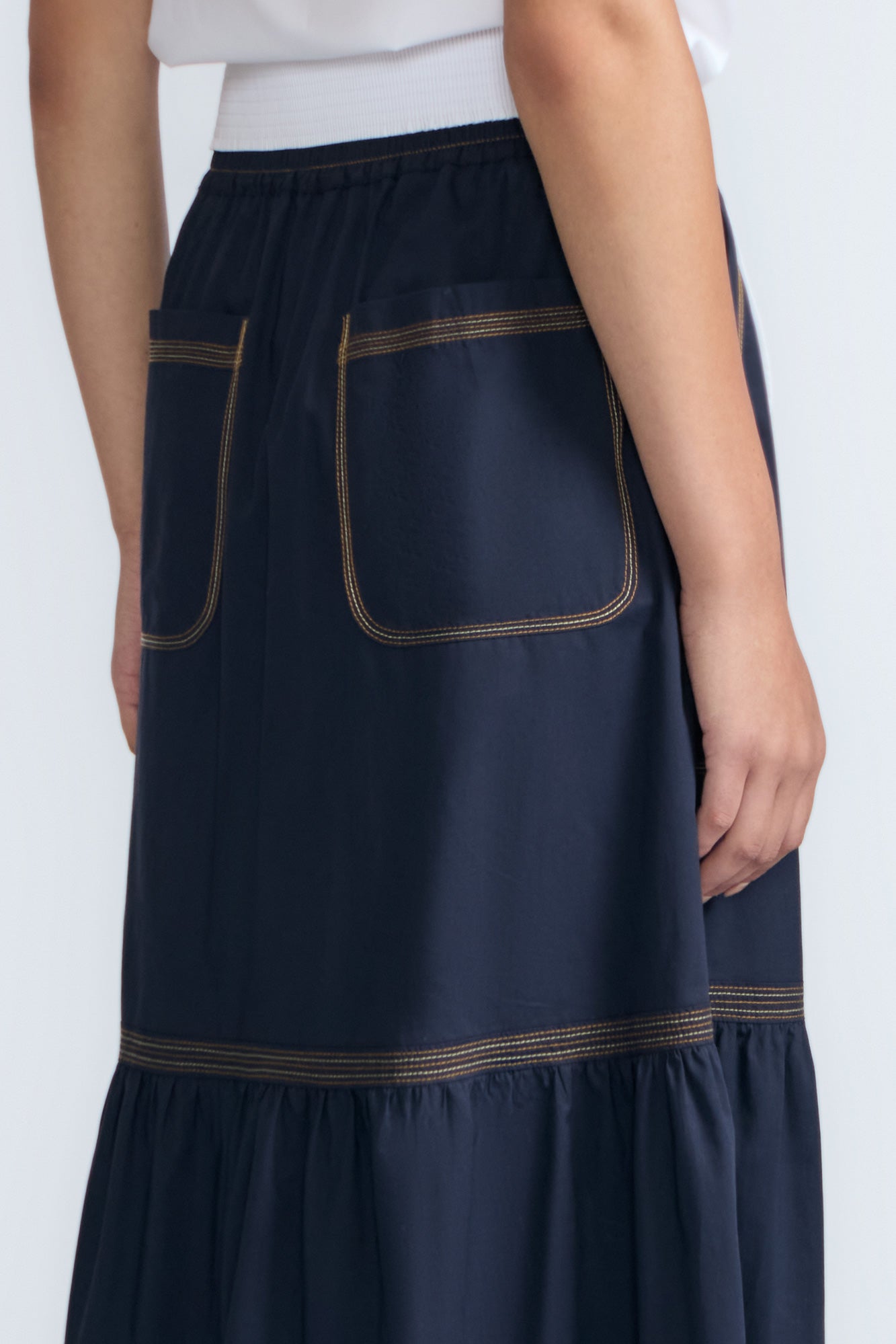 Eden Skirt in Navy – Cotton midi skirt with ruffled hem, front patch pockets, and elasticized back waistband.