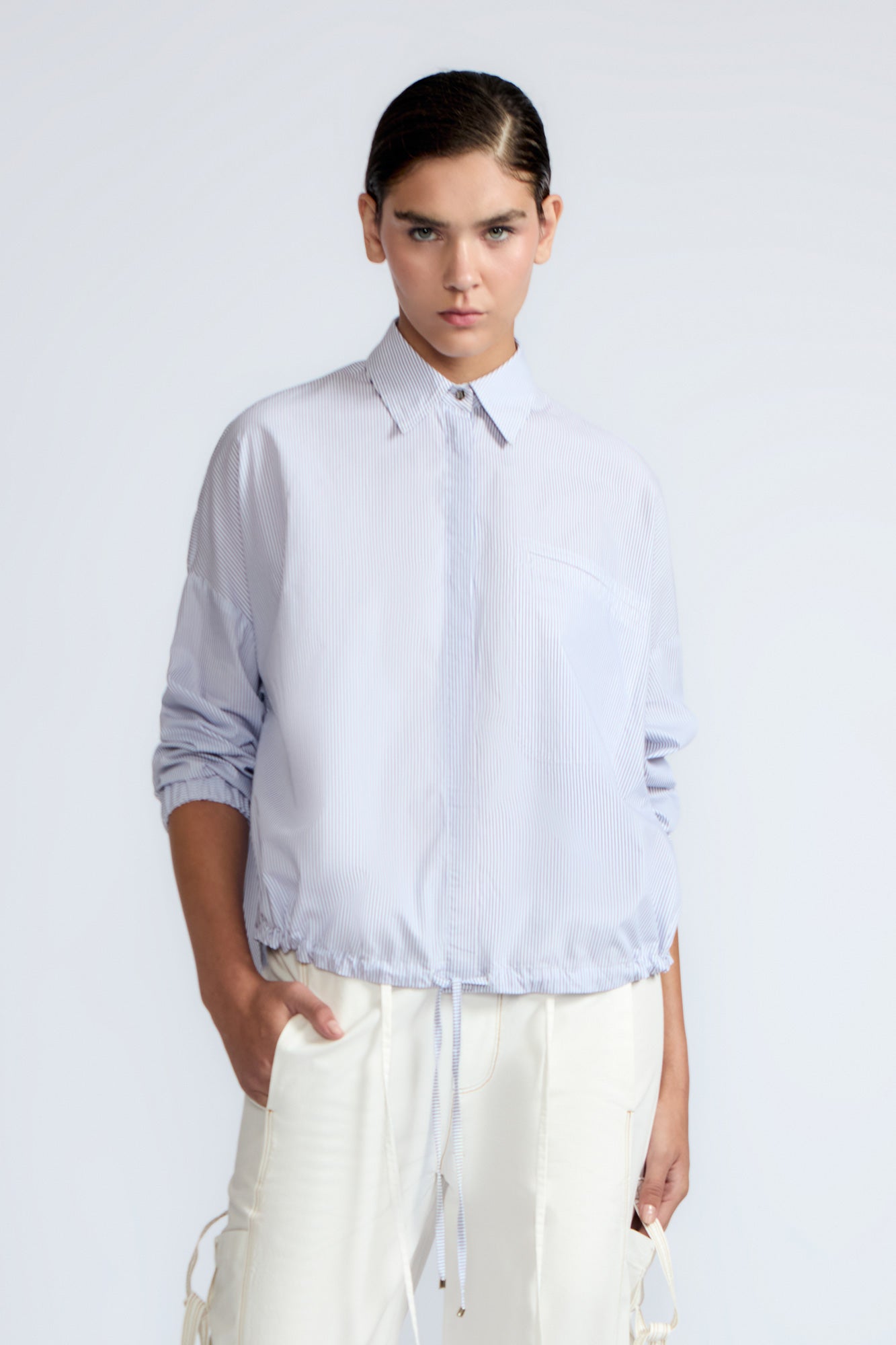 Hebe Blouse in Light Blue Stripes – Relaxed blouse with lapel collar, hidden buttons, asymmetrical hem, and elasticized long sleeves.