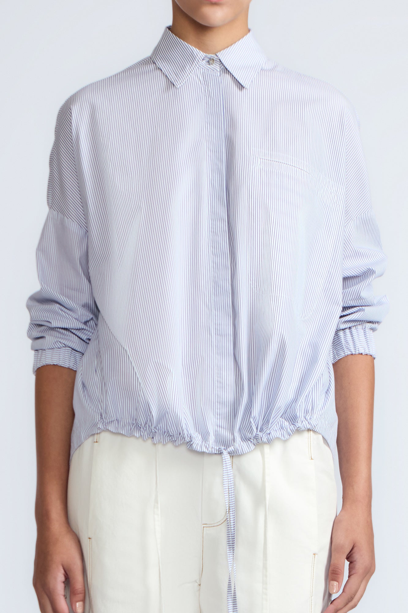 Hebe Blouse in Light Blue Stripes – Relaxed blouse with lapel collar, hidden buttons, asymmetrical hem, and elasticized long sleeves.