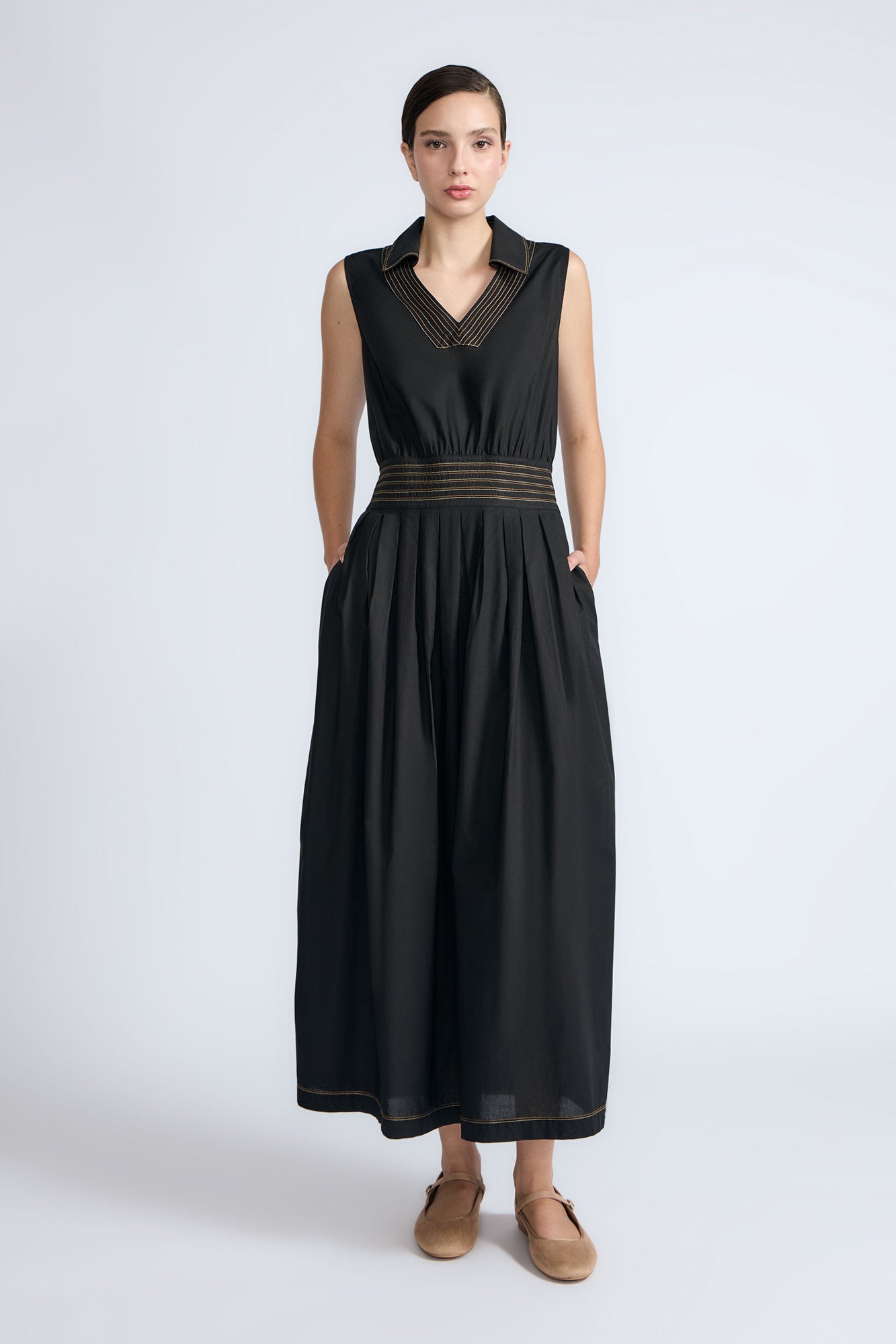 Isidora Dress in Black – Sleeveless midi cotton dress with shirt collar V-neckline, tiered silhouette, and hidden side pockets.
