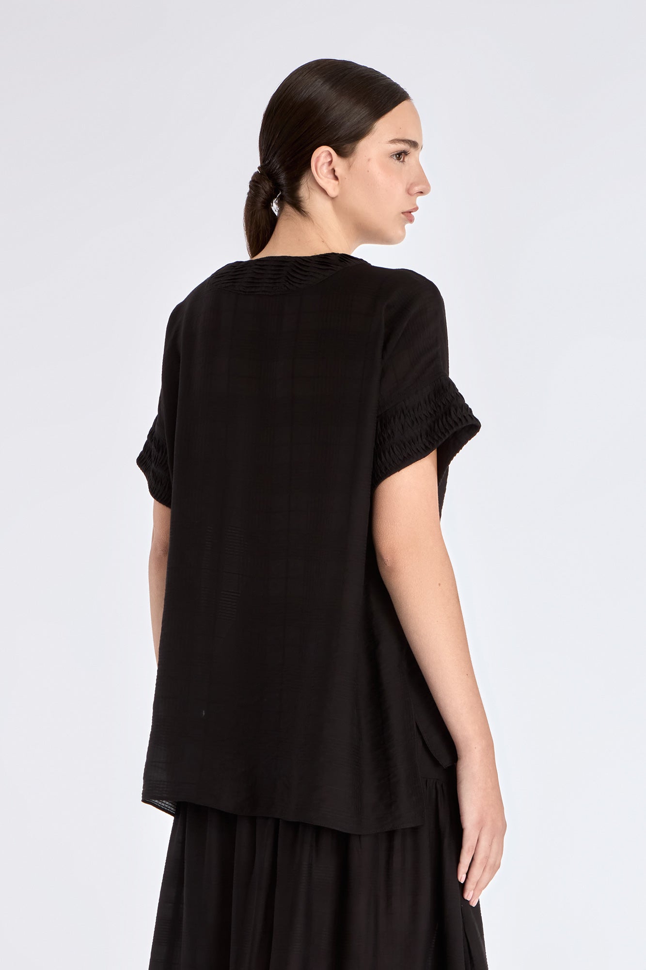 Ivy Blouse in Black – Short sleeve blouse with V-neckline and refined hem detailing, crafted in a soft rayon blend.