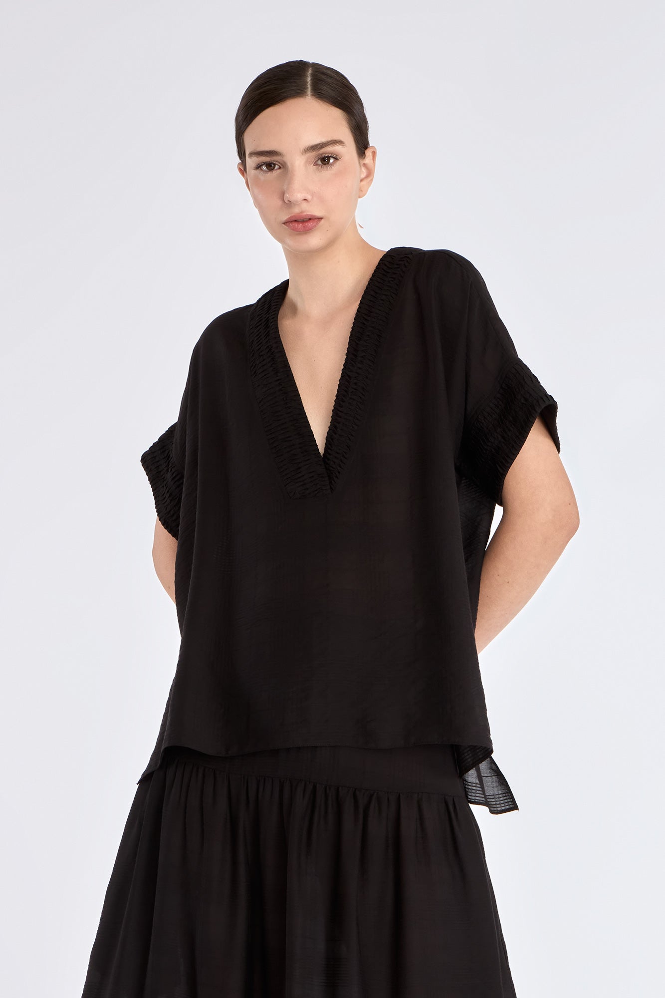Ivy Blouse in Black – Short sleeve blouse with V-neckline and refined hem detailing, crafted in a soft rayon blend.