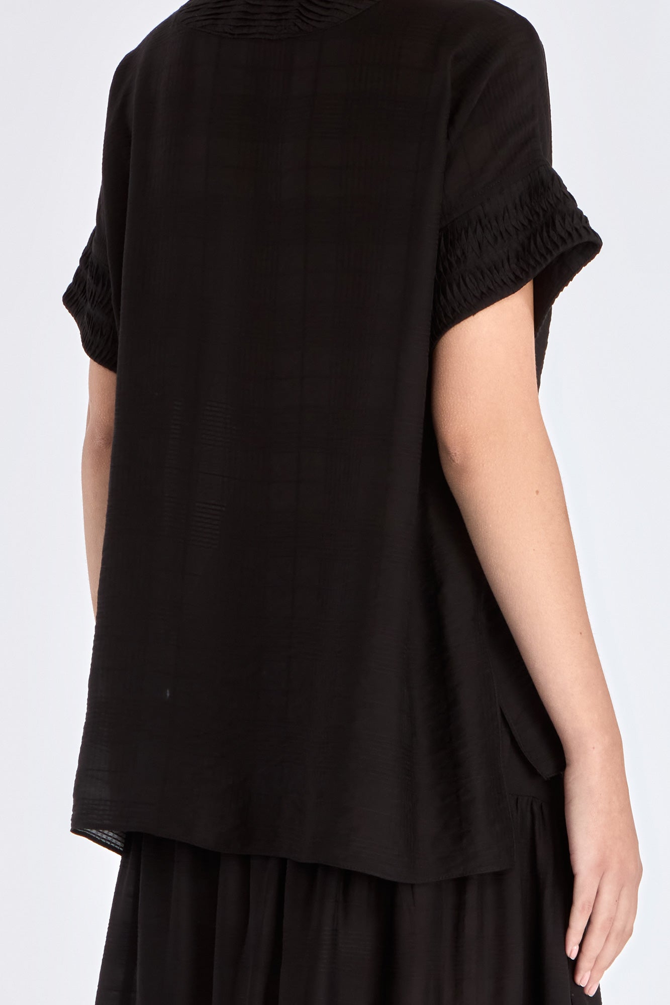 Ivy Blouse in Black – Short sleeve blouse with V-neckline and refined hem detailing, crafted in a soft rayon blend.
