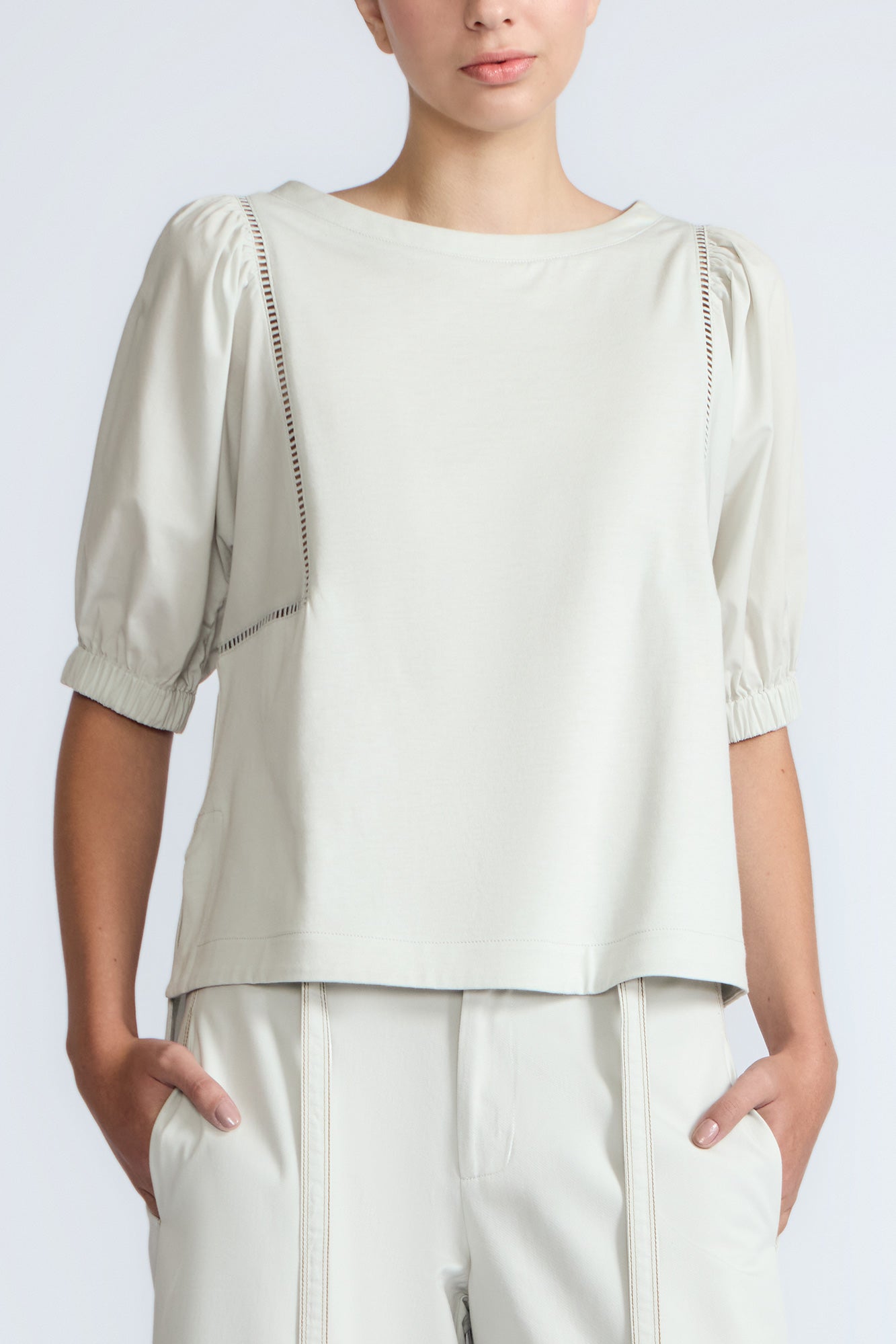 Woman wearing a light-colored blouse with puffed sleeves on a white background