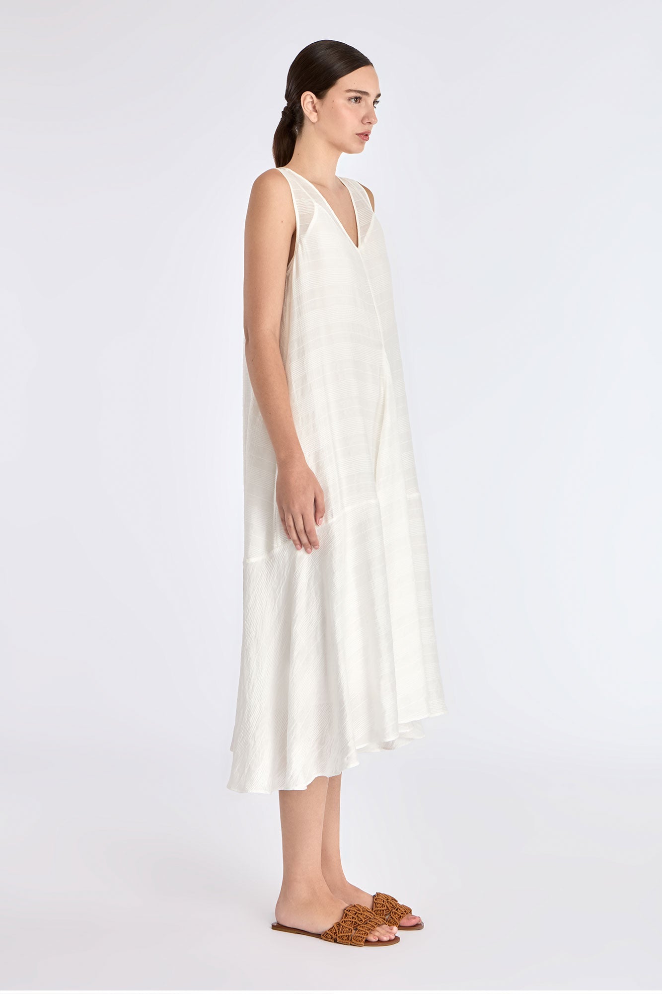The Off White Lenox Dress shown in profile, highlighting the flared godet skirt.