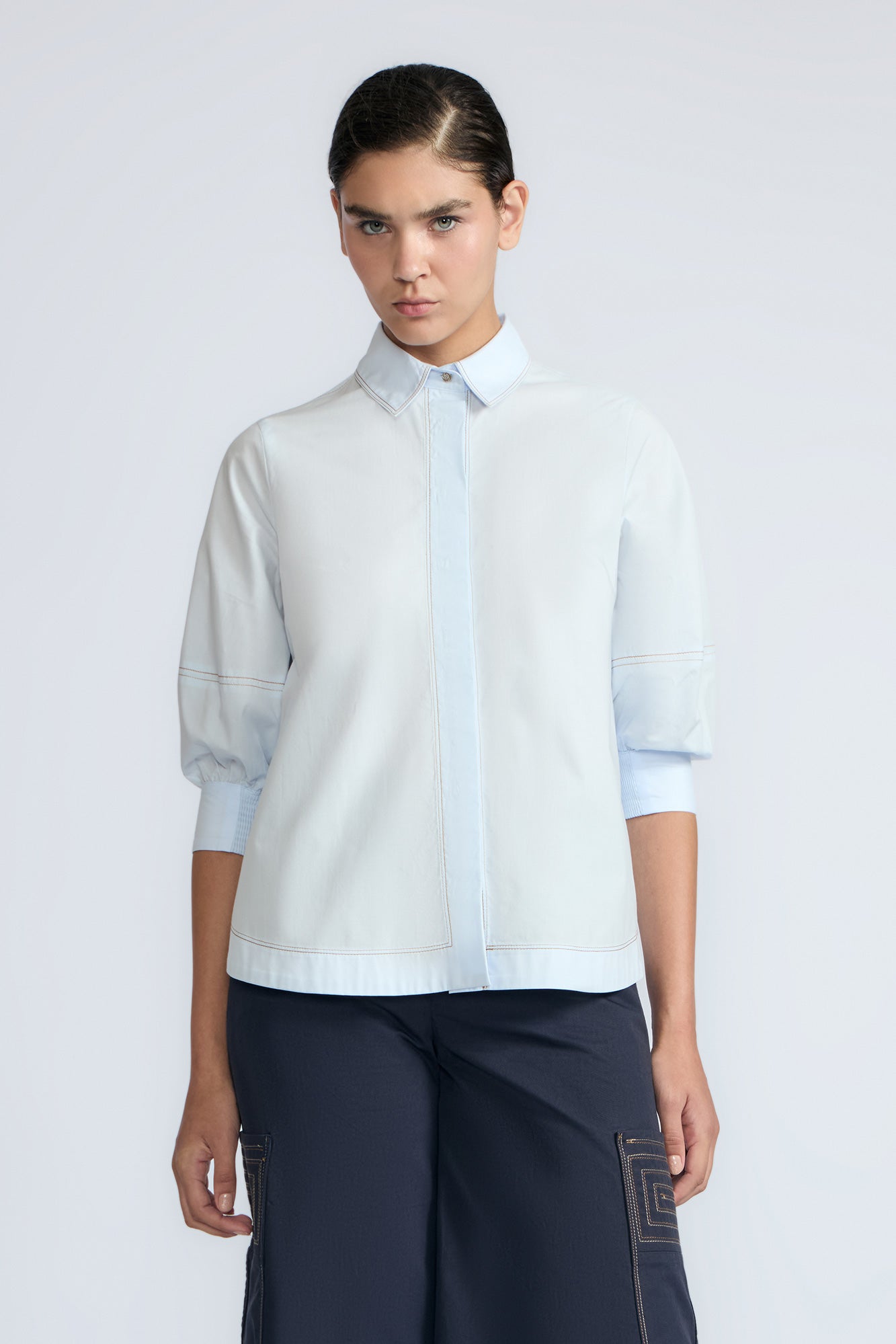 Lina Blouse in Light Blue – Cotton shirt with shirt collar, hidden button closure, ¾ balloon sleeves, and elastic cuffs.