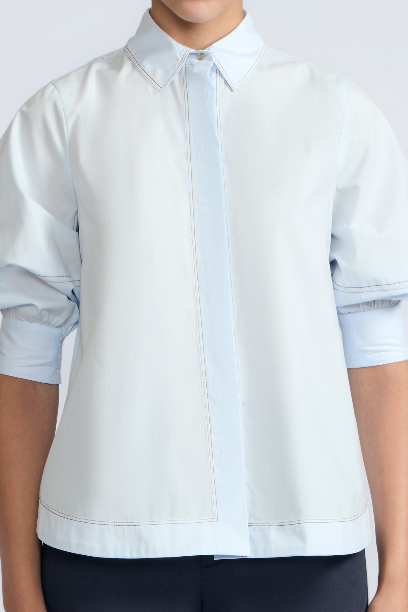 Lina Blouse in Light Blue – Cotton shirt with shirt collar, hidden button closure, ¾ balloon sleeves, and elastic cuffs.