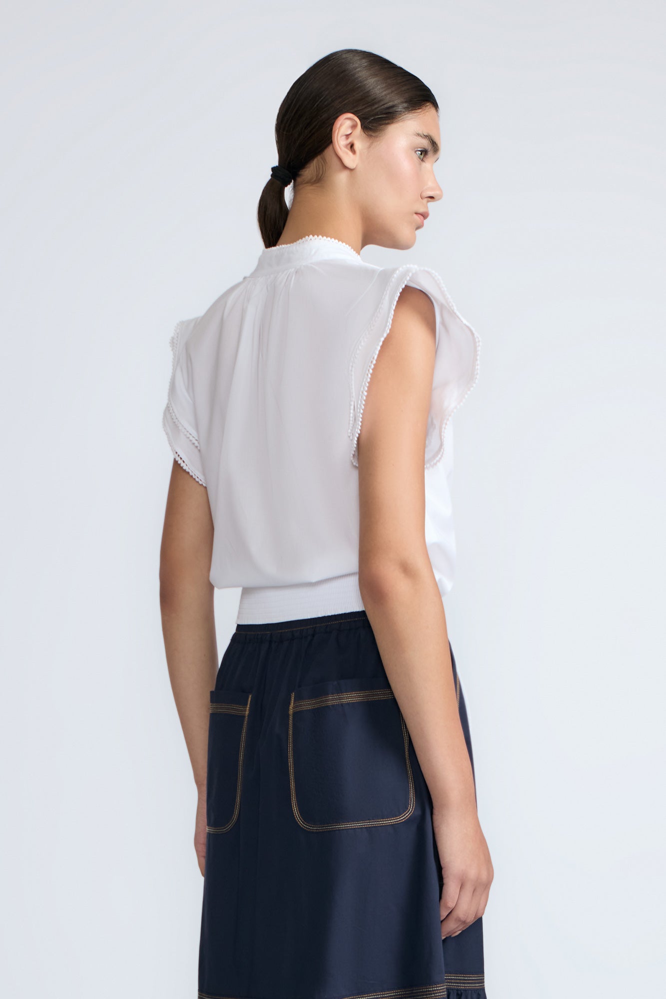 Oriana Blouse in White – Elegant cotton blouse with V-neck, Neru collar, ruffle sleeves, tie waist, and hand-appliqué detailing.