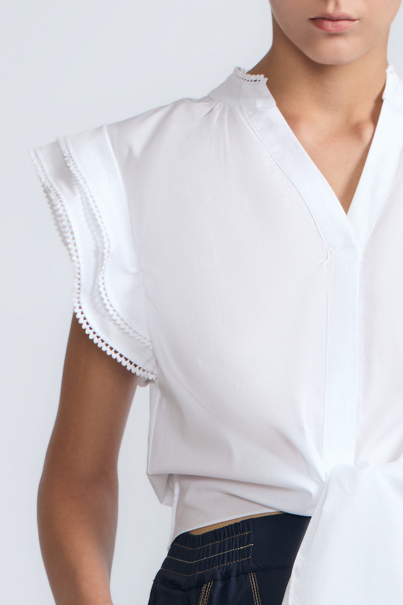 Oriana Blouse in White – Elegant cotton blouse with V-neck, Neru collar, ruffle sleeves, tie waist, and hand-appliqué detailing.