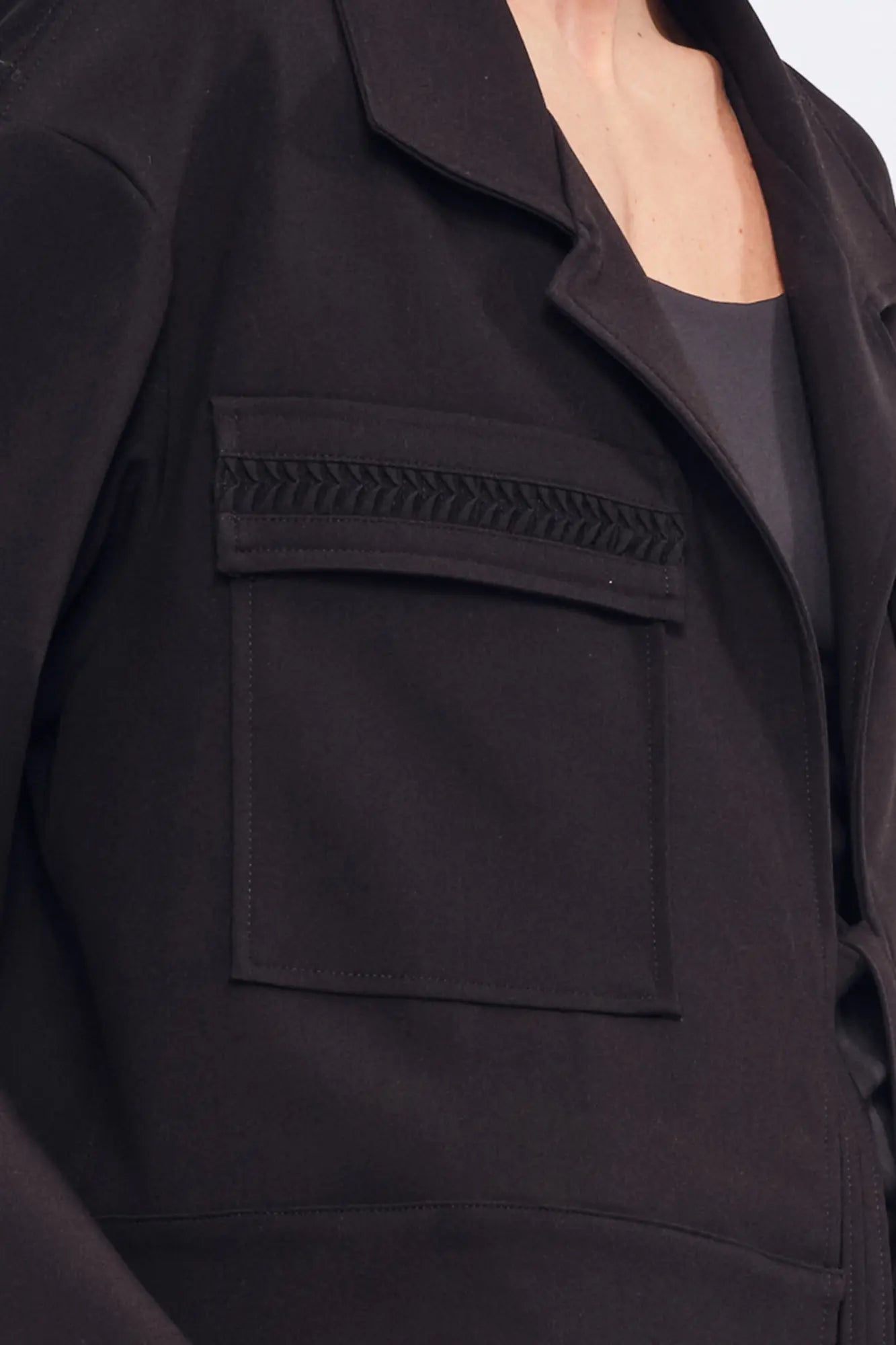 Detail shot of the tonal, raised gathered texture on the flap pocket of the black Parker Jacket.