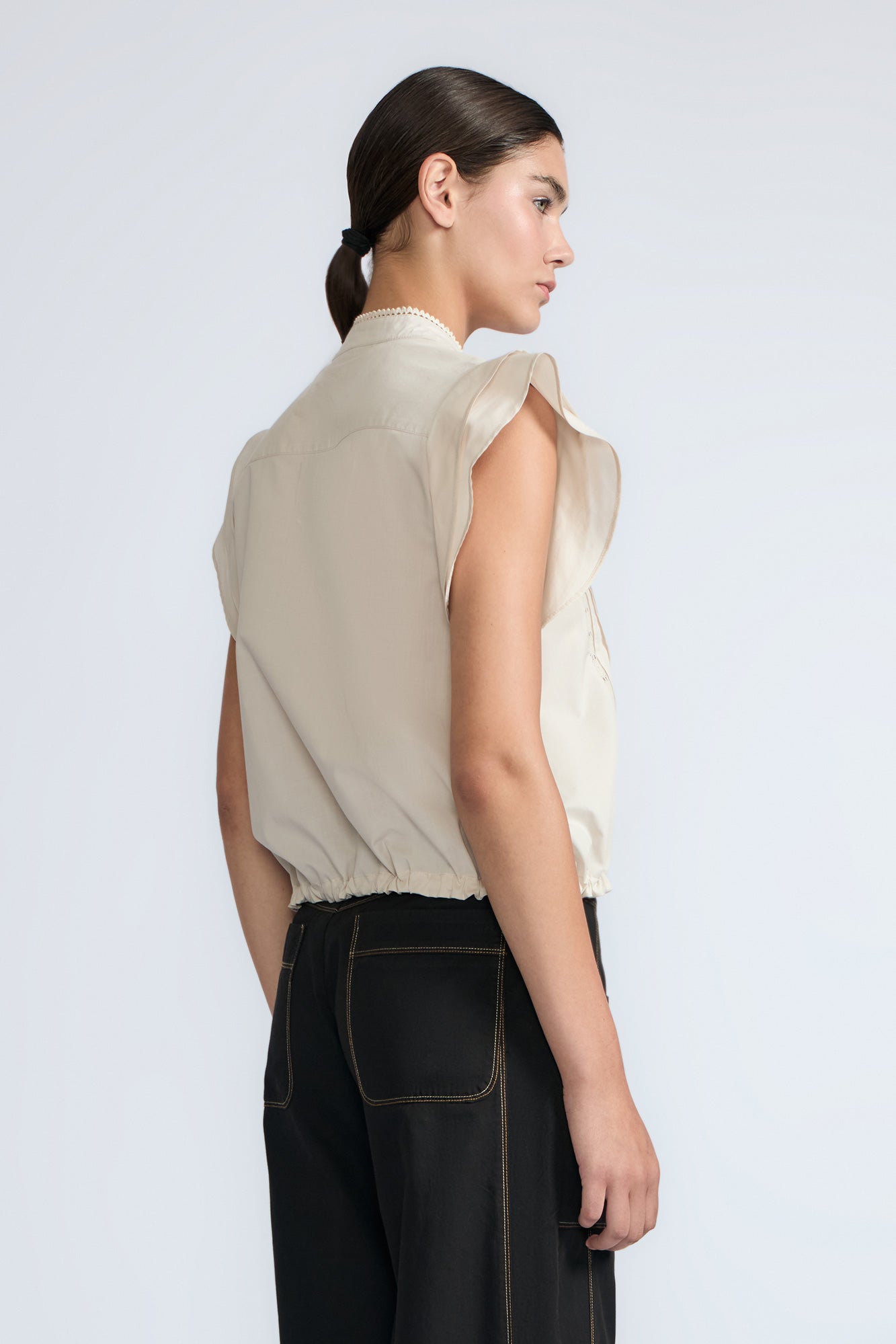 Pria Blouse in Prestine – Elegant sleeveless blouse in pima cotton with tonal V-neck, Greca trim, ruffle detail, and hem with pullers.