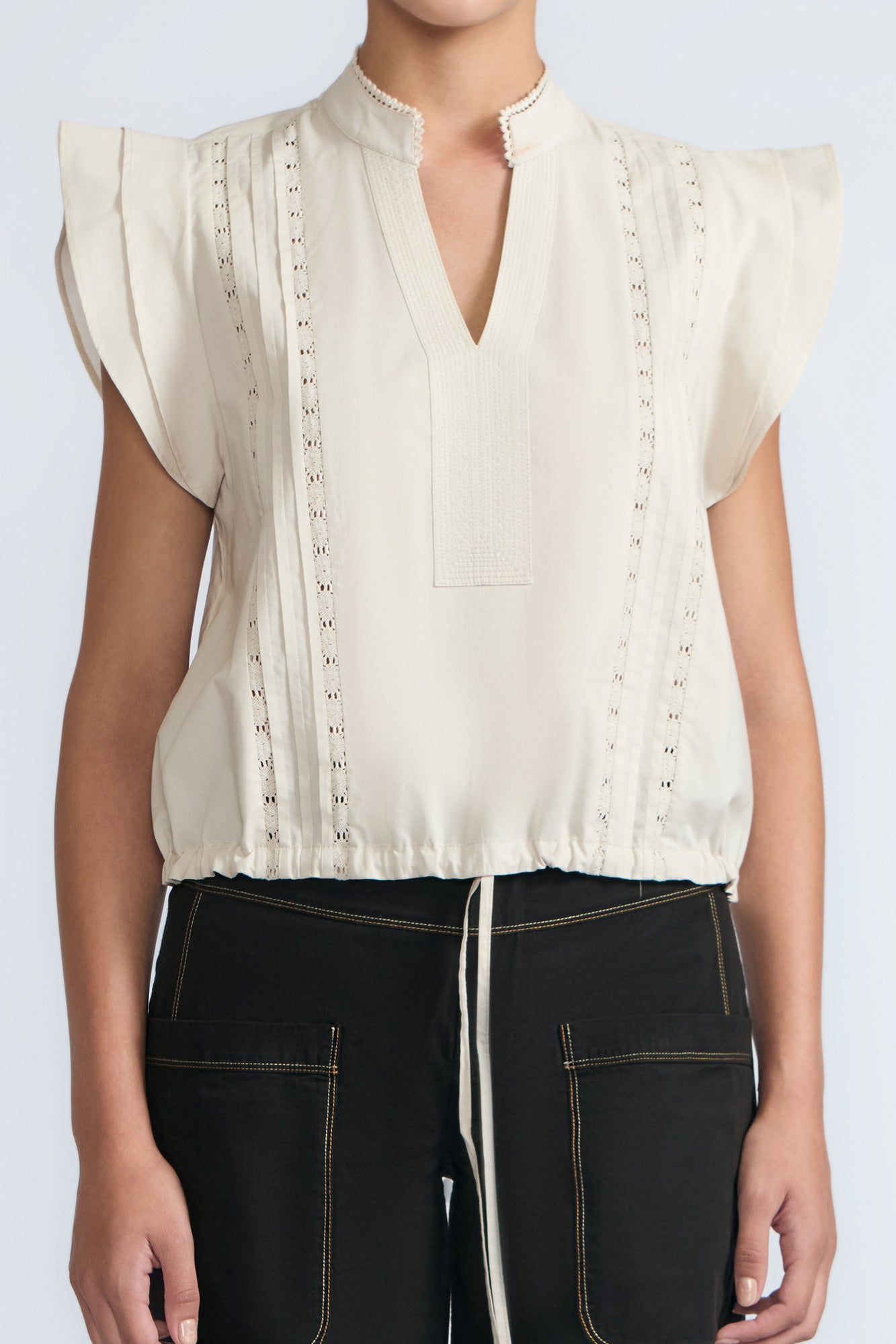 Pria Blouse in Prestine – Elegant sleeveless blouse in pima cotton with tonal V-neck, Greca trim, ruffle detail, and hem with pullers.